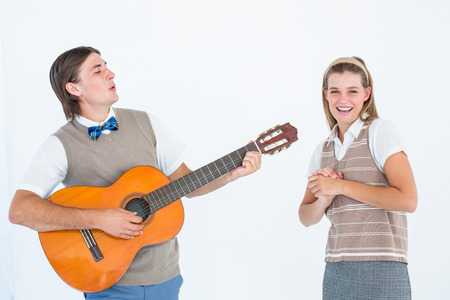 Geeky hipster serenading his girlfriend with guitar on white backgroundの写真素材