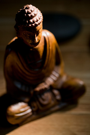 Wooden buddha statue on table shot in studioの写真素材