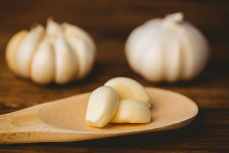 Garlic cloves and bulb on chopping board with copy spaceの写真素材