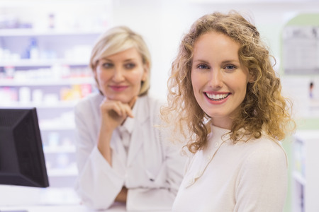 Pharmacist and costumer smiling at camera at pharmacyの写真素材