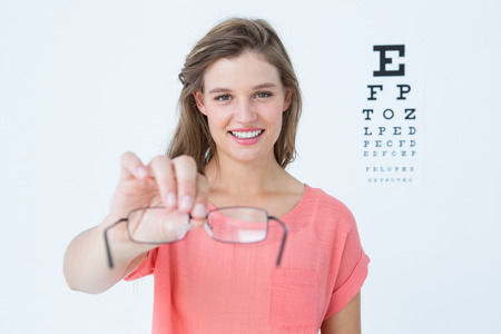 Hipster showing glasses next to an eye test on white backgroundの写真素材
