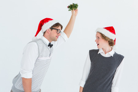 Geeky hipster holding mistletoe on white backgroundの写真素材