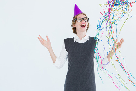 Happy geeky hipster wearing a party hat on white backgroundの写真素材
