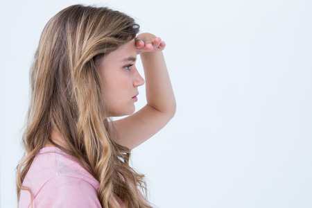 Pretty blonde looking the horizon with hand on forehead on white backgroundの写真素材