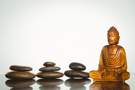 Wooden buddha statue with balancing pebbles shot in studioの写真素材