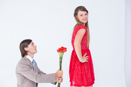 Hipster on bended knees behind his girlfriend on white backgroundの写真素材