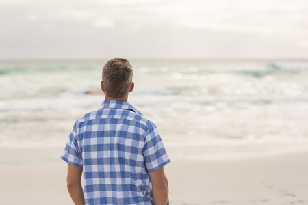 Casual man looking out to sea at the beach
