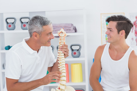 Doctor showing anatomical spine to his patient in medical office