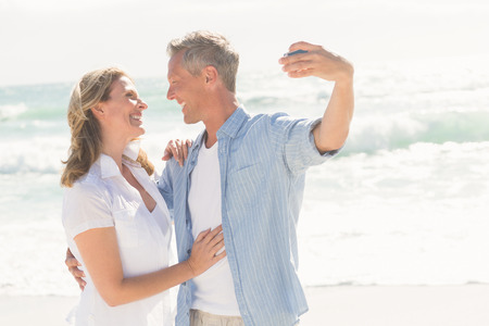 Happy couple taking a selfie at the beachの写真素材