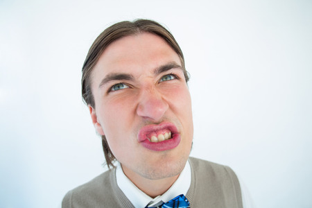 Geeky hipster grimacing on white background
