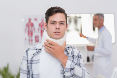 Patient with neck brace looking at camera in medical officeの写真素材
