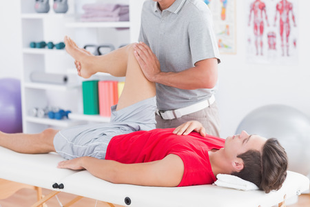 Physiotherapist doing leg massage to his patient in medical officeの写真素材