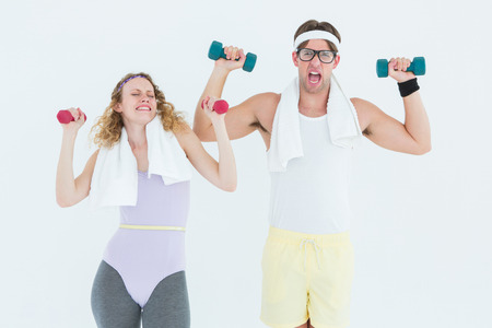 Geeky hipster couple lifting dumbbells in sportswear on white backgroundの写真素材