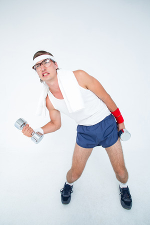 Geeky hipster lifting dumbbells in sportswear on white backgroundの写真素材