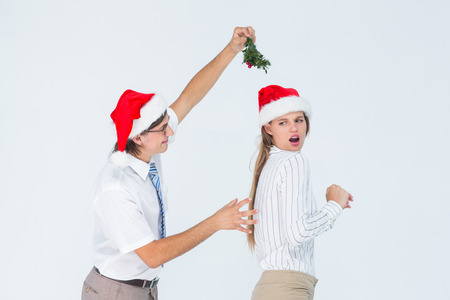 Geeky hipster running away from a man with mistletoe on white backgroundの写真素材