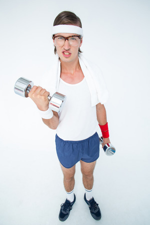 Geeky hipster lifting dumbbells in sportswear on white backgroundの写真素材