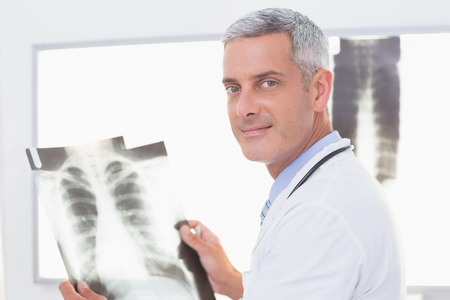 Smiling doctor looking at X-Rays in medical office