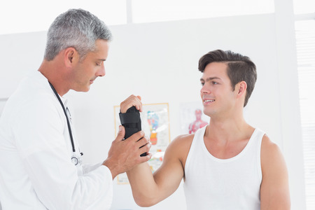 Doctor examining a man wrist in medical officeの写真素材