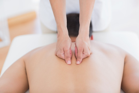 Physiotherapist doing back massage to her patient in medical officeの写真素材