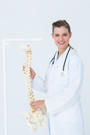 Doctor holding an anatomical spine on white backgroundの写真素材