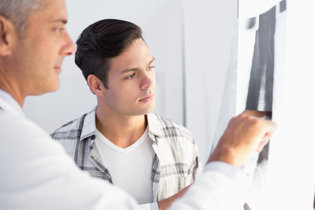 Doctor showing X rays to his patient in medical officeの写真素材