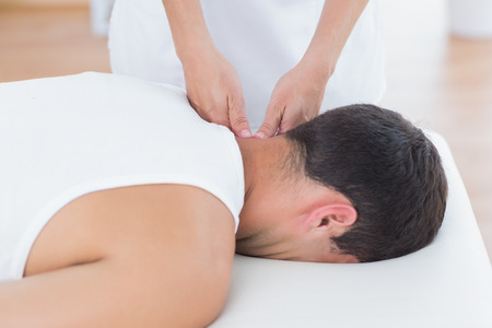 Physiotherapist doing neck massage in medical officeの写真素材