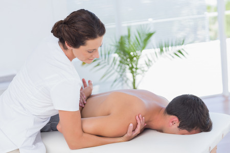 Physiotherapist doing shoulder massage to her patient in medical officeの写真素材