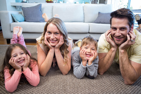 Happy family smiling at camera at home in the living roomの写真素材