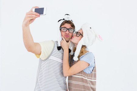 Geeky hipster couple taking selfie with smartphone on white backgroundの写真素材