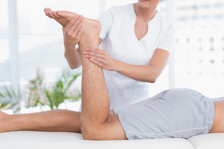 Physiotherapist doing leg massage to her patient in medical officeの写真素材