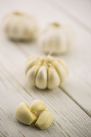 Garlic cloves and bulb on chopping board with copy spaceの写真素材