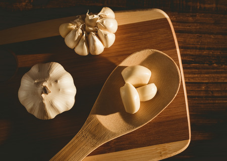 Garlic cloves and bulb on chopping board with copy spaceの写真素材