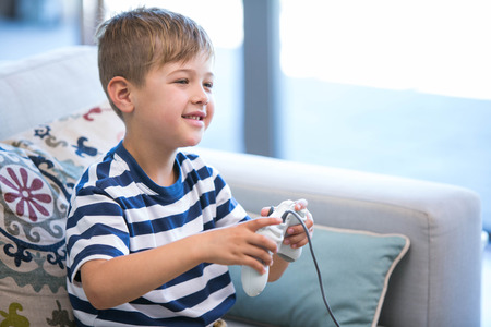 Little boy playing video games at home in the living room