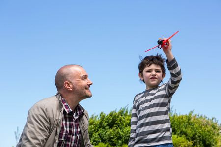 Young boy playing with a toy plane in the countryside