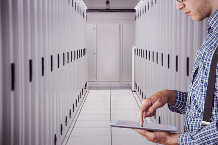 Geeky businessman using his tablet pc against data centerの写真素材