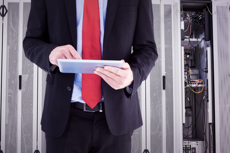Businessman scrolling on his digital tablet against data center