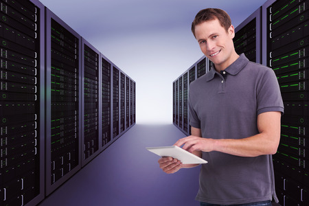 Smiling young man with tablet computer against server hallway