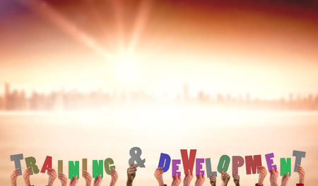 Hands holding up training and development against sun shining over cityの写真素材