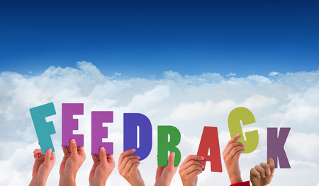 Hands holding up feedback against bright blue sky over cloudsの写真素材