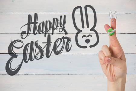 Fingers as easter bunny against painted blue wooden planksの写真素材