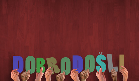 Hands holding up dobrodosli against wooden planksの写真素材