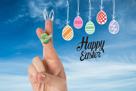 Fingers as easter bunny against blue skyの写真素材