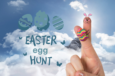 Fingers as easter bunny against mountain peak through the cloudsの写真素材