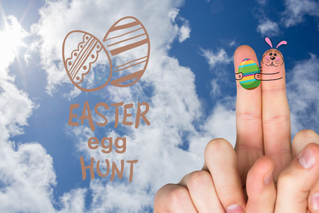 Fingers as easter bunny against bright blue sky with cloudsの写真素材