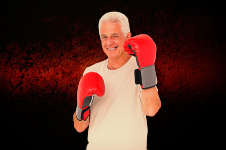 Senior man in boxing gloves against dark backgroundの写真素材