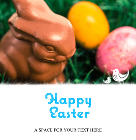 happy easter against chocolate bunny with easter eggsの写真素材