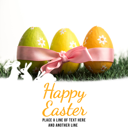happy easter against three easter eggs wrapped in pink ribbonの写真素材
