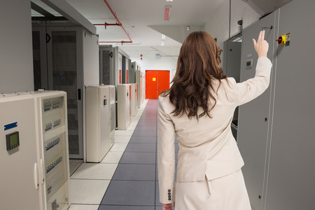 Brunette businesswoman standing back to camera against data center