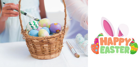 Happy mother and daughter painting easter eggs  against happy easter graphicの写真素材