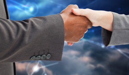 Business handshake  against lines against glowing skyの写真素材